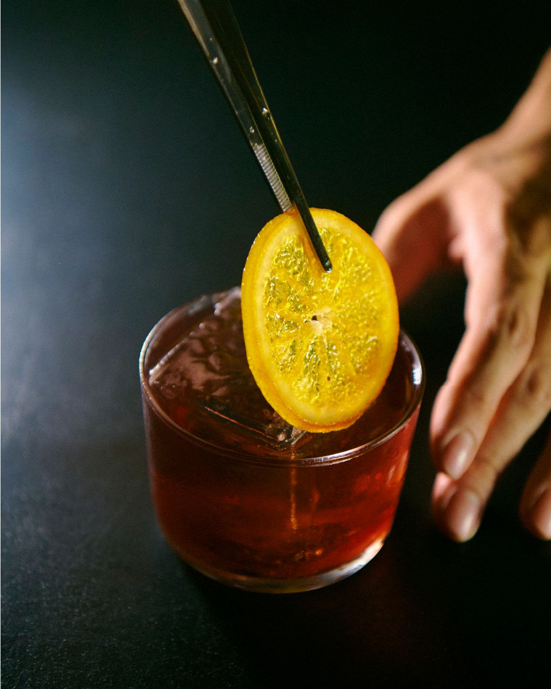 Bartender terminando un trago con rodaja de naranja deshidratada