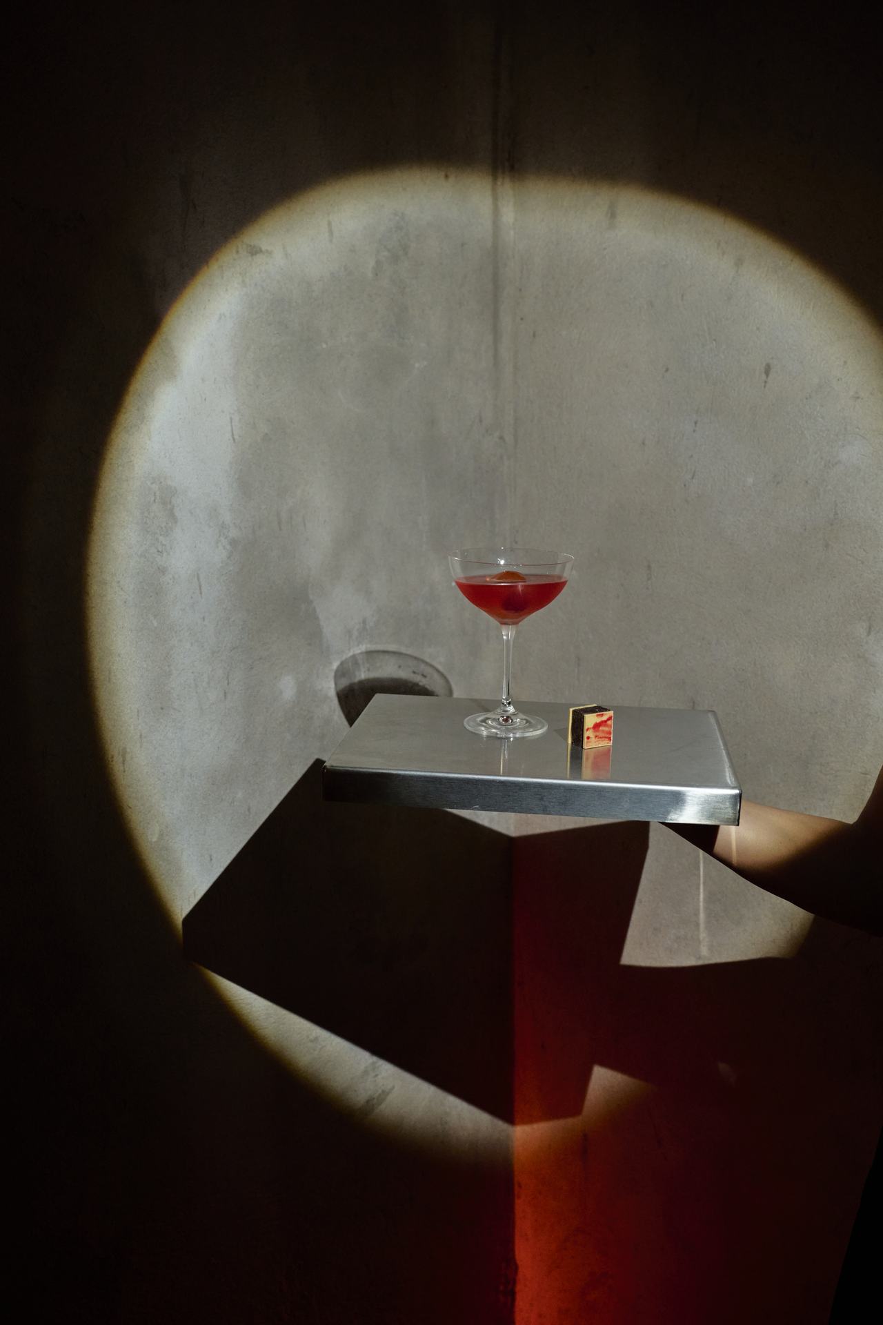 Copa de trago rojo bajo un círculo de luz, lanzamiento Stella McCartney × H&M