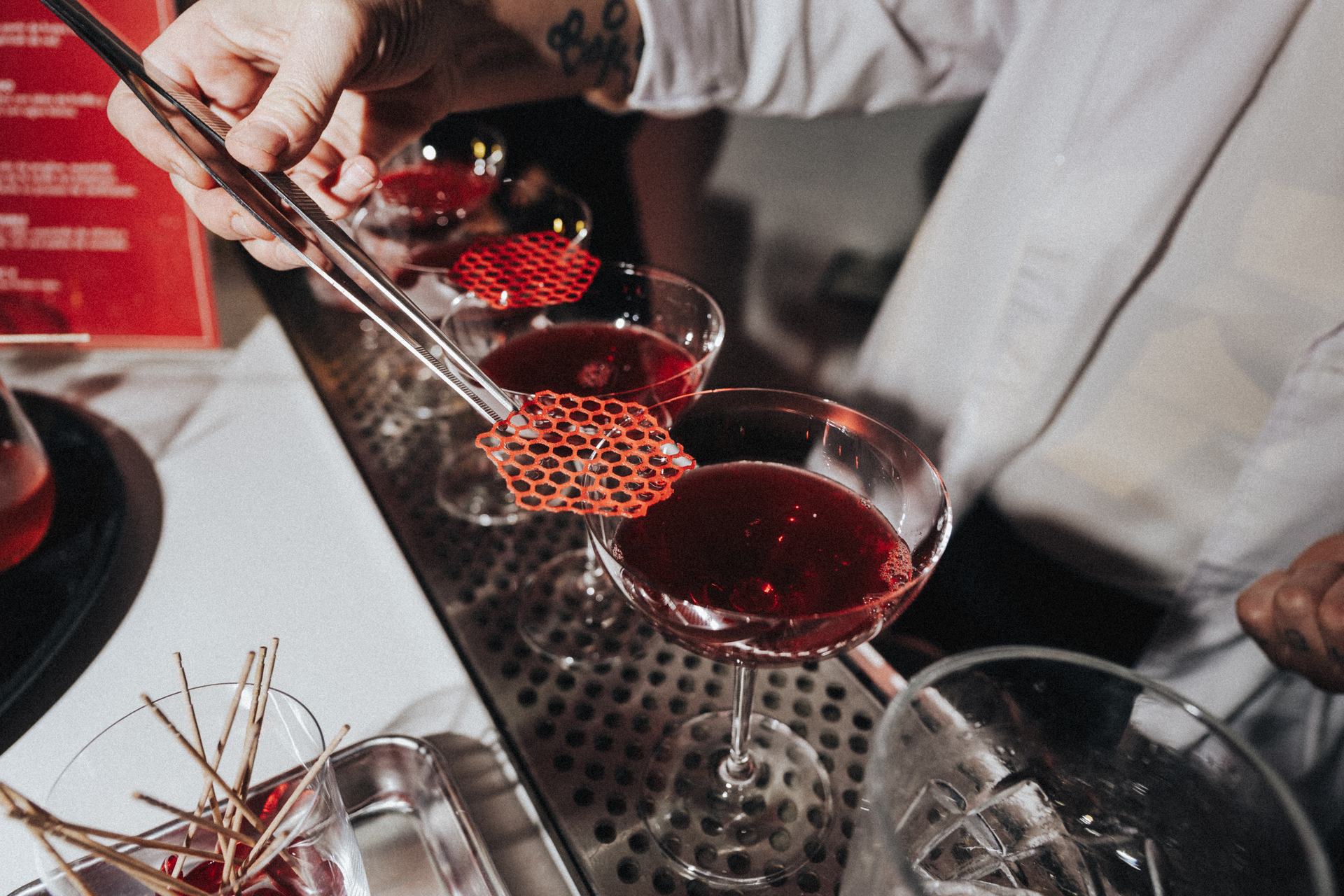 Bartender colocando la red de Vichy sobre una copa de trago rojo, activación de Vichy